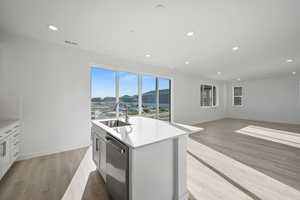 Kitchen with white cabinetry, recessed lighting, light wood finished floors, a kitchen island with sink, and stainless steel dishwasher