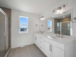 Full bath with double vanity and a shower stall