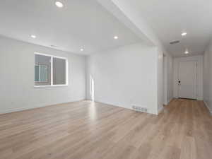 Empty room with light wood-style floors and recessed lighting