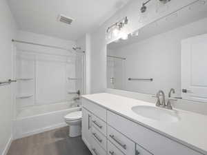Bathroom featuring shower / bath combination, vanity, and dark tile patterned floors