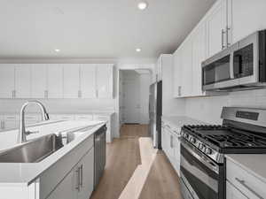 Kitchen with appliances with stainless steel finishes, backsplash, light wood-style flooring, light stone counters, and recessed lighting