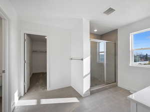Full bathroom with a shower stall, a spacious closet, vanity, and light tile patterned floors