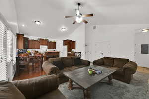 Living room featuring electric panel, high vaulted ceiling, wood finished floors, and ceiling fan