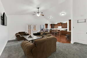 Living room featuring gray colored carpet, high vaulted ceiling, and ceiling fan
