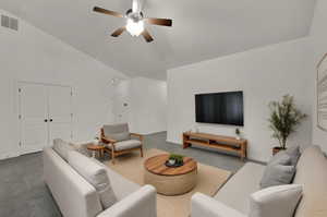 Carpeted living room with high vaulted ceiling and ceiling fan