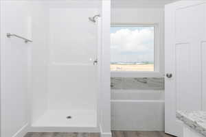 Full bath with a stall shower, a bath, and light wood finished floors