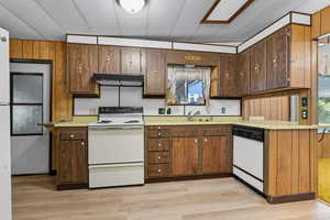Kitchen featuring white appliances, light countertops, healthy amount of natural light, and under cabinet range hood