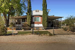 View of front facade with a fenced front yard, covered porch, a carport, and a gate