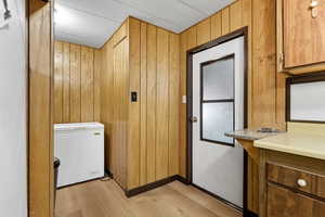 Washroom featuring wooden walls and light wood-style floors