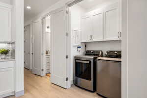 Washroom with light wood-style flooring, cabinet space, washer and clothes dryer, and recessed lighting
