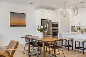 Dining room with light wood-type flooring and recessed lighting