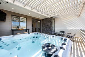 Wooden deck featuring a pergola, a hot tub, and a patio