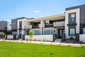 Rear view of property featuring a balcony, stucco siding, and a yard