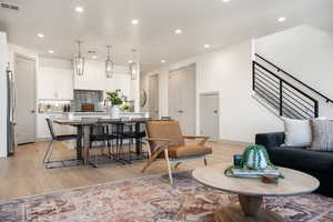 Living area with recessed lighting, stairway, and light wood finished floors