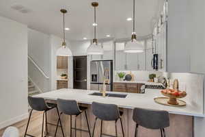 Kitchen with a breakfast bar area, glass insert cabinets, a peninsula, recessed lighting, and light wood-style floors