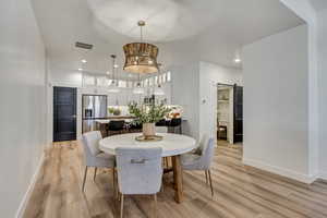 Dining room featuring a barn door, light wood finished floors, recessed lighting, and a chandelier