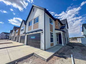 View of side of home featuring a residential view, a garage, stone siding, and concrete driveway