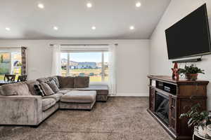Living area with carpet, vaulted ceilings, large window and recessed lighting