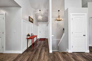 Foyer with vaulted ceiling, a chandelier, and dark wood-style floors