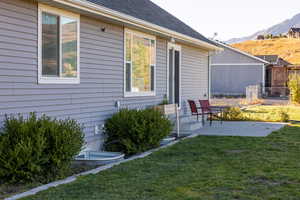 Rear view of house with a patio area, roof with shingles, and a mountain view