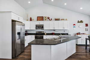 Kitchen featuring stainless steel appliances, dark wood-style floors, white cabinets, high vaulted ceiling, and recessed lighting