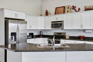 Kitchen featuring white cabinets, appliances with stainless steel finishes, and dark countertops