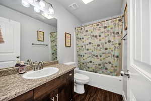 Hall bathroom with shower / bath combination with curtain, vanity, and dark wood-style floors