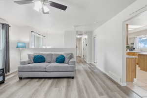 Living area featuring a chandelier, light wood-type flooring, and ceiling fan