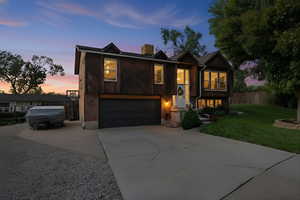 Split foyer home with driveway, a chimney, an attached garage, and brick siding