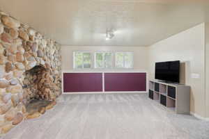 Unfurnished living room with carpet floors, a fireplace, and a textured ceiling