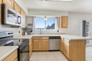 Kitchen with stainless steel appliances, a peninsula, light countertops, and plenty of natural light