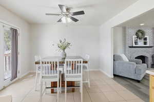 Dining area with light tile patterned floors, a fireplace, and ceiling fan