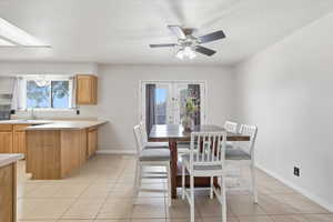 Dining space featuring light tile patterned floors, a textured ceiling, ceiling fan, and french doors