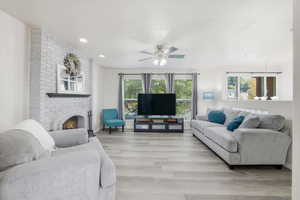 Living room featuring plenty of natural light, a fireplace, light wood-style floors, ceiling fan, and recessed lighting