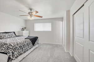 Bedroom with light carpet, a ceiling fan, and a closet