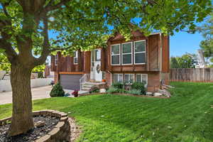Raised ranch with brick siding, concrete driveway, and an attached garage