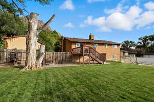 Rear view of property featuring a fenced backyard, stairs, a patio, a wooden deck, and a chimney
