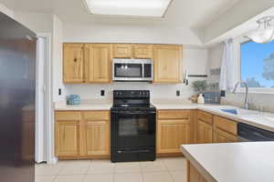Kitchen with stainless steel appliances, light countertops, and light tile patterned floors
