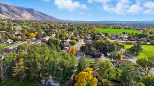 Aerial view of property and surrounding area featuring mountains and nearby suburban area
