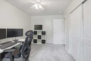 Home office with light colored carpet and ceiling fan