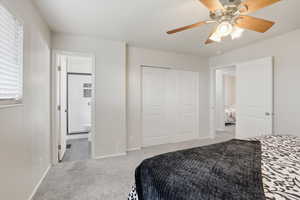 Tiled bedroom featuring carpet floors, a closet, ceiling fan, and ensuite bathroom