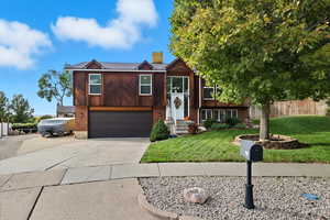 Split foyer home with brick siding, concrete driveway, a chimney, and a garage