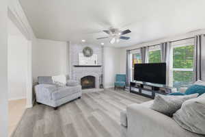 Living room with a fireplace, light wood finished floors, a ceiling fan, and recessed lighting