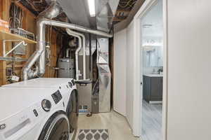 Laundry room featuring water heater, washer and dryer, and heating unit