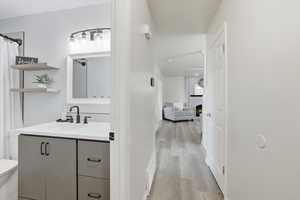 Full bath with vanity, light wood-style flooring, and a brick fireplace