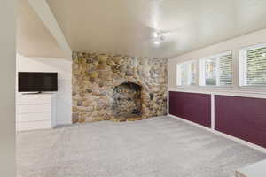 Unfurnished living room with carpet floors, a textured ceiling, and a fireplace