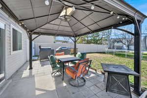 Fenced backyard featuring a gazebo, outdoor dining space, a patio area, and area for grilling