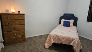 Bedroom with dark carpet and baseboards
