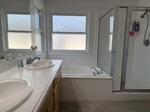 Primary bathroom with a double vanity, a large jetted bathtub, separate shower and light tile patterned floors