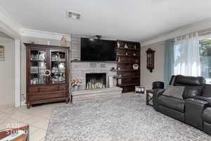 Living area featuring crown molding, light tile patterned floors, a fireplace, and a textured ceiling